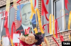 Портрет президента России Владимира Путина на торжественной церемонии, посвященной окончанию учебного года, в средней школе № 18 в Грозном, Чечня, 25 мая 2022 года