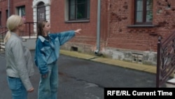 Алика показывает следы от пуль времен Второй мировой войны на здании в Нарве