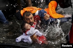 Беженец из Сирии пытается удержать ребенка во время падения на берегу у острова Лесбос. 24 сентября 2015